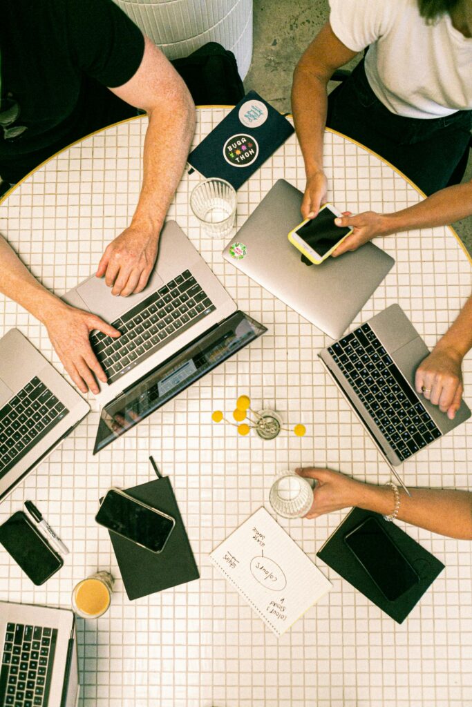 Many hands and laptops on a table